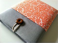 an orange and gray cover with a wooden button on the front is sitting on a white table