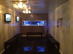 a fish tank in the corner of a room with two benches and a tv mounted to the wall