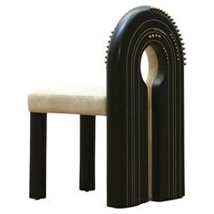 a black and white chair sitting next to a wooden stool with an oval design on it