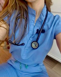 a woman wearing a blue scrub suit with a stethoscope on her neck