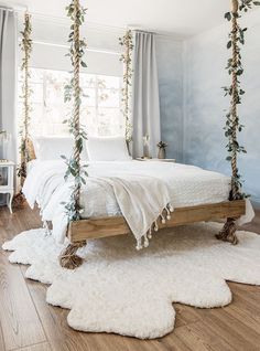 a white bed sitting on top of a wooden frame in a bedroom next to a window