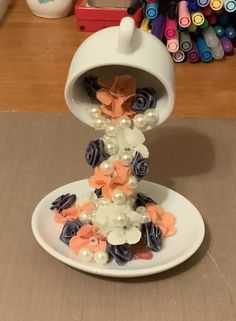 there is a white plate with flowers and pearls on it, next to crayons