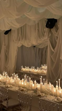 the tables are covered with white draping and lit candles