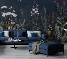 a blue couch sitting in front of a wall with flowers and birds painted on it