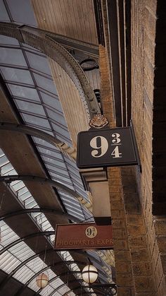 a sign hanging from the side of a building next to a tall clock tower with glass windows