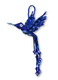 a blue beaded hummingbird hanging on a white wall in the shape of a bird