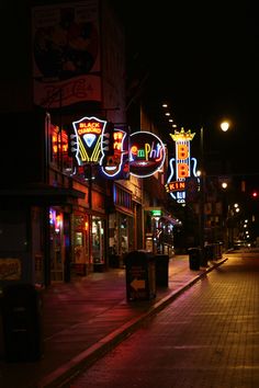 an empty city street at night with neon signs