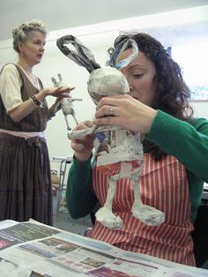 two women in aprons are working on sculptures