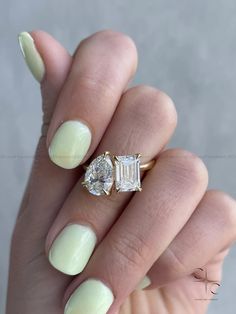 a woman's hand holding a ring with two stones on it and a diamond in the middle