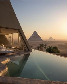 an outdoor swimming pool with the pyramids in the background at sunset or sunrise time