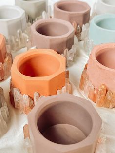 several different colored vases sitting on top of a white table covered in ice crystals