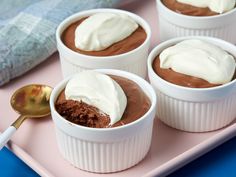 three small cups filled with chocolate pudding on a pink tray