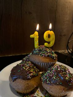 three cupcakes on a plate with candles in the shape of number thirteen and one chocolate frosted muffin