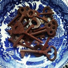 there are many old rusty keys on the blue and white plate