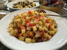 a white plate topped with food next to bowls filled with fruit and veggies