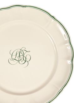 a white plate with green trimming and a monogrammed initial on the side