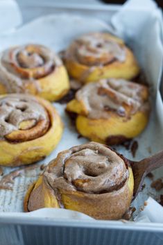 cinnamon rolls in a baking pan with a wooden spoon