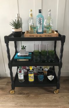 a bar cart with gin bottles and glasses on it