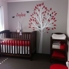 a baby's room with a tree painted on the wall and two cribs