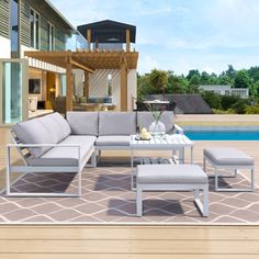 a couch and table on a patio next to a pool with a gazebo in the background