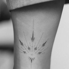 a black and white photo of a woman's leg with an arrow tattoo on it