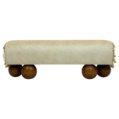 an upholstered bench with three wooden balls on the bottom and two large round legs