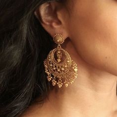 a close up of a woman's ear wearing gold earrings with filigrees