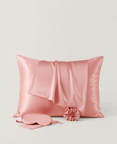 the pink satin pillow is next to it's matching cover and two decorative pillows