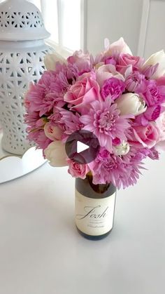 a vase filled with pink and white flowers on top of a table next to a lamp