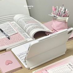 an open book sitting on top of a desk next to a keyboard and pen holder