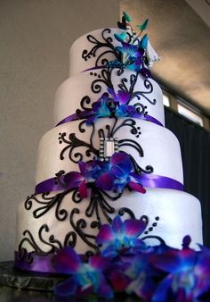 a wedding cake with purple and blue flowers on it