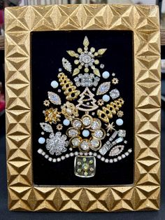 a gold frame with a christmas tree made out of jewels and pearls in the center