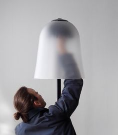 a woman holding a lamp up to the ceiling in front of her face and head