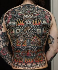 the back of a man with tattoos on his upper and lower half is covered in flames