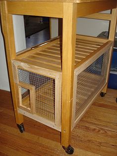 a wooden table with a small cage on it's bottom shelf and wheels underneath