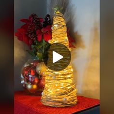 a christmas tree made out of tinsel next to a vase with red and white flowers