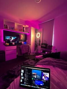 a laptop computer sitting on top of a bed in a room with purple lighting and furniture