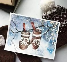 a pair of mittens sitting on top of a table next to a christmas card