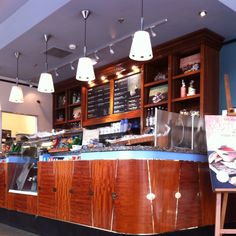 an empty restaurant with wooden counter tops and lights hanging from the ceiling over the bar