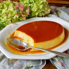 a piece of cheesecake with caramel sauce on a plate next to a spoon