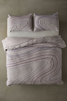 a bed with two pillows on top of it next to a pillow case and blanket