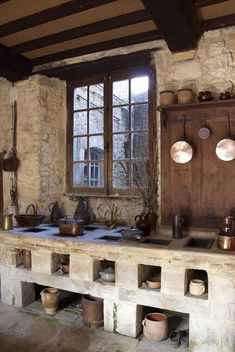 an old fashioned kitchen with pots and pans on the stove top in front of a window