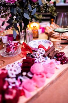 a table topped with lots of different types of candies and wine glasses next to each other