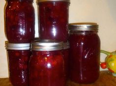 several jars filled with red liquid sitting on top of a wooden table