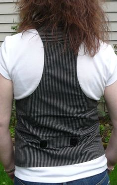 the back of a person with long red hair standing in front of a white house