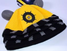 a yellow and black knitted hat sitting on top of a white table next to a computer mouse