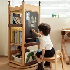 a little boy that is sitting in a chair with a chalkboard on the wall