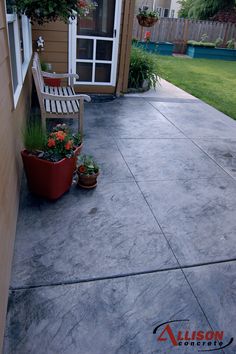 a wooden bench sitting on top of a cement patio next to a flower potted plant