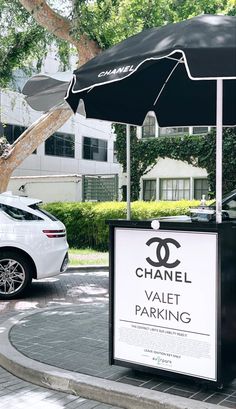 a chanel parking booth with an umbrella on the side walk next to a white car