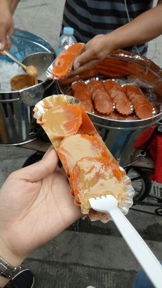 a person holding food in their hand near other bowls and spoons on the ground